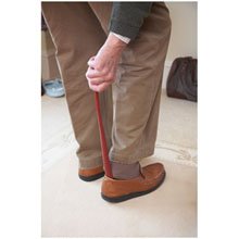 elderly man using a long shoe horn to put shoes on 