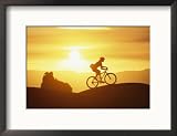 A Woman Rides Her Bike in the Sunset with Rock Cliffs in the Background Framed Photographic Poster Print by Dugald Bremner, 21x17