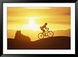 A Woman Rides Her Bike in the Sunset with Rock Cliffs in the Background Framed Photographic Poster Print by Dugald Bremner, 44x32