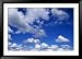 Sunlit Fluffy White Clouds in a Blue Sky Framed Photographic Poster Print by Jason Edwards, 45x33