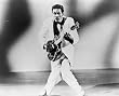 1957 photo Chuck Berry, full-length portrait, standing, facing front, playing guitar.