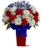 Patriotic Petals: A Beautiful arrangement of red, white and blue flowers in a red glass vase.