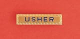 Usher Pin: Handsome 1 3/8x5/16 Inches Gold Bar with Safety Catch. Usher in Dark Blue Enameled Letters.