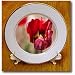A Very Close Up of a Red Bulb Flower With a Yellow Center and Blurred Background of Green - 8 Inch Porcelain Plate