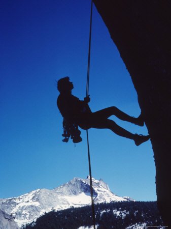 A Rock Climber Rappeling Down a Cliff