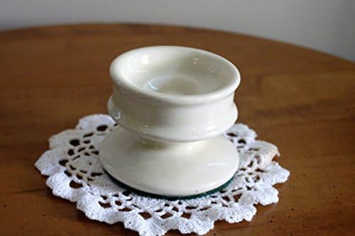 A small, round, glossy cream colored ceramic candleholder.