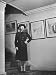 Alice Roosevelt Longworth Wearing a Suit and Hat, Standing in Hallway with Paintings ...