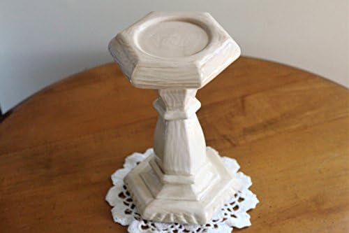 A tall, solid bone colored, hexagon shaped ceramic candleholder.