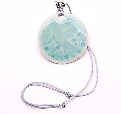 A true porcelain pendant with a hummingbird in the mountains motif. The pendant is about 2.1 in or 5.3cm. dia., Lanyard is of adjustable and about 26 in. total length.