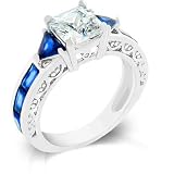 White Gold Rhodium Bonded with Radiant and Trillion Cut Sapphire Crystals and Round Cut Clear CZ Handset Along the Shank and Prong Set Princess Cut Center Stone in Silvertone