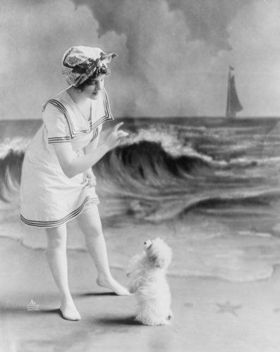 1913 photo Young woman in bathing suit with small dog in front of studio backdrop of beach
