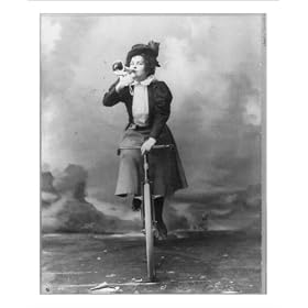 Historic Print (S): [Madge Lessing, full length, on bicycle, facing left; holding musical horn to lips]