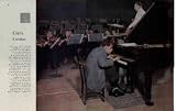 The Face of America: Chilly Genius. Twenty-six-year-old Glenn Gould is, in his fashion, an eccentric. He is also a genius. Music critics place him in the top rank of concert pianists, and his eccentricities are plain for all to see, as in this close-up of Gould rehearsing a Bach piano concerto with the Detroit Symphony Orchestra. To get his nose close to the keyboard, Gould has his piano up on blocks and uses a lowered chair. The chair legs end in screwjacks, which he adjusts and readjusts between solo passages. The Ford Auditoreum is so warm that conductor Paul Paray has shucked his coat, but Canadian-born Gould is padded against a lifelong chill. His muffler, sweater and heavy jacket, the rug under his feet, the glass of warm mineral water on the piano - all year-round equipment. He soaks his hands in hot water before playing, wears gloves and a cap between takes, and needs an overcoat even in summer. Presumably it all helps; that music is glorious. Photograph by Ormond Gigli. ..... 1959 Saturday Evening Post Picture, A5229A.