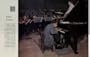 The Face of America: Chilly Genius. Twenty-six-year-old Glenn Gould is, in his fashion, an eccentric. He is also a genius. Music critics place him in the top rank of concert pianists, and his eccentricities are plain for all to see, as in this close-up of Gould rehearsing a Bach piano concerto with the Detroit Symphony Orchestra. To get his nose close to the keyboard, Gould has his piano up on blocks and uses a lowered chair. The chair legs end in screwjacks, which he adjusts and readjusts between solo passages. The Ford Auditoreum is so warm that conductor Paul Paray has shucked his coat, but Canadian-born Gould is padded against a lifelong chill. His muffler, sweater and heavy jacket, the rug under his feet, the glass of warm mineral water on the piano - all year-round equipment. He soaks his hands in hot water before playing, wears gloves and a cap between takes, and needs an overcoat even in summer. Presumably it all helps; that music is glorious. Photograph by Ormond Gigli. ..... 1959 Saturday Evening Post Picture, A5229A. 19590404