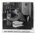 Historic Print (L): [Government official seated at his desk wearing head phones and tuning small radio]