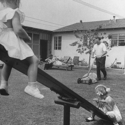 Man Pushing Lawnmower over Grass While Daughters Play and Wife Loafs in Backyard Stretched Canvas Poster Print Man Pushing Lawnmower over Grass While Daughters Play and Wife Loafs in Backyard Stretched Canvas Poster Print