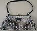 Multi colored knitted fabric clutch purse with small black vinyl decorative bow on front side / has Black vinyl bottom / top with vinyl strap and silver pinch clasp with 1 zippered compartment pre owned