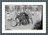 Photo (L): 4 men rolling barrel in park