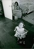 Vintage photo of Princess Margaretha, sitting on a couch, watching at her daughter playing with her bike.