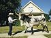 A Cowboy Uses a Harness to Lead His Bull Along a Suburban Sidewalk Photographic Poster Print by Joel