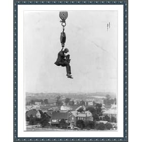 Historic Print (XL): [Photographer with camera suspended from hook of a (crane?) high in the air]