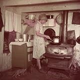Woman Stands at Old-Fashioned Stove to Cook, Cats Prowl at Her Feet Stretched Canvas Poster Print by Justin Locke, 24x24