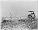 Tractor pulling large set of discs across field,c1900
