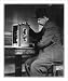 Historic Print (L): [Man seated with a stamp vending machine]