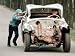 A Boy Pushes an Abandoned and Damaged Car as Another Boy Steers It Photographic Poster Print, 48x64