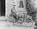 Photographic Prints of Man on an early motorcycle in front of a house from Mary Evans