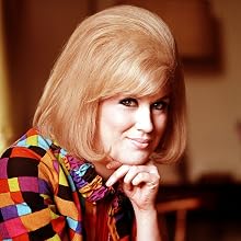 Dusty Springfield - 1965. A facial portrait of the famous British singer Dusty Springfield sitting at home smiling at the camera.